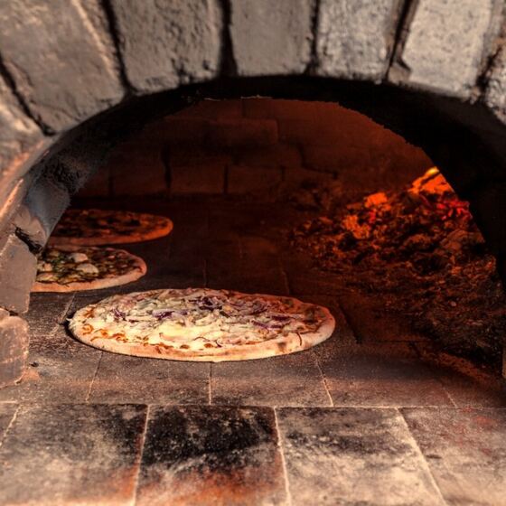 Pizza vytahovaná z pece na dřevo